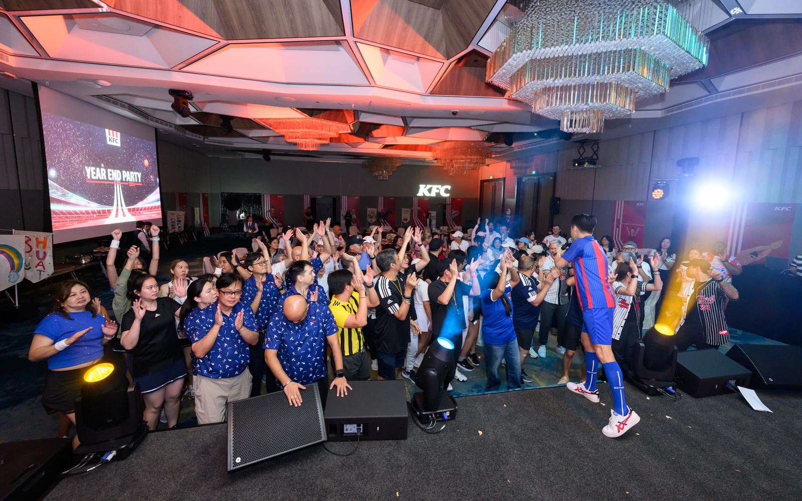 Large group of event participants raising their hands during a hosted programme