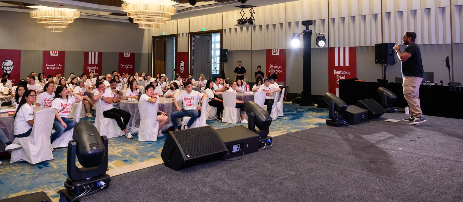 Facilitator briefing a seated audience during an indoor company event